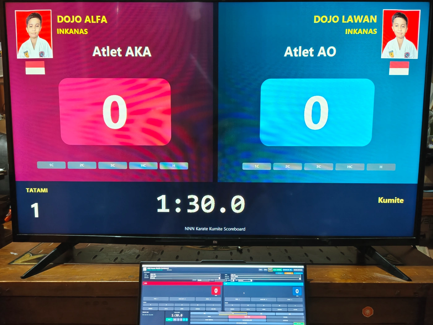 Aplikasi papan skor digital PapanSkor.id pada laptop dan layar penonton