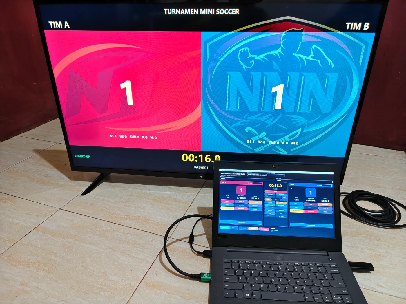 Papan skor Mini Soccer digital digunakan operator dengan tampilan TV atau monitor publik