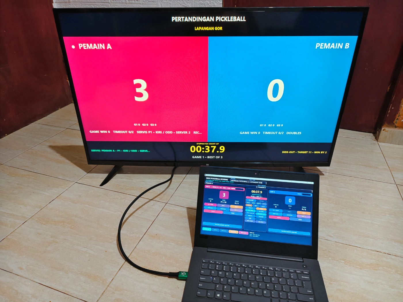 Papan skor Pickleball digital digunakan operator dengan public scoreboard pada TV